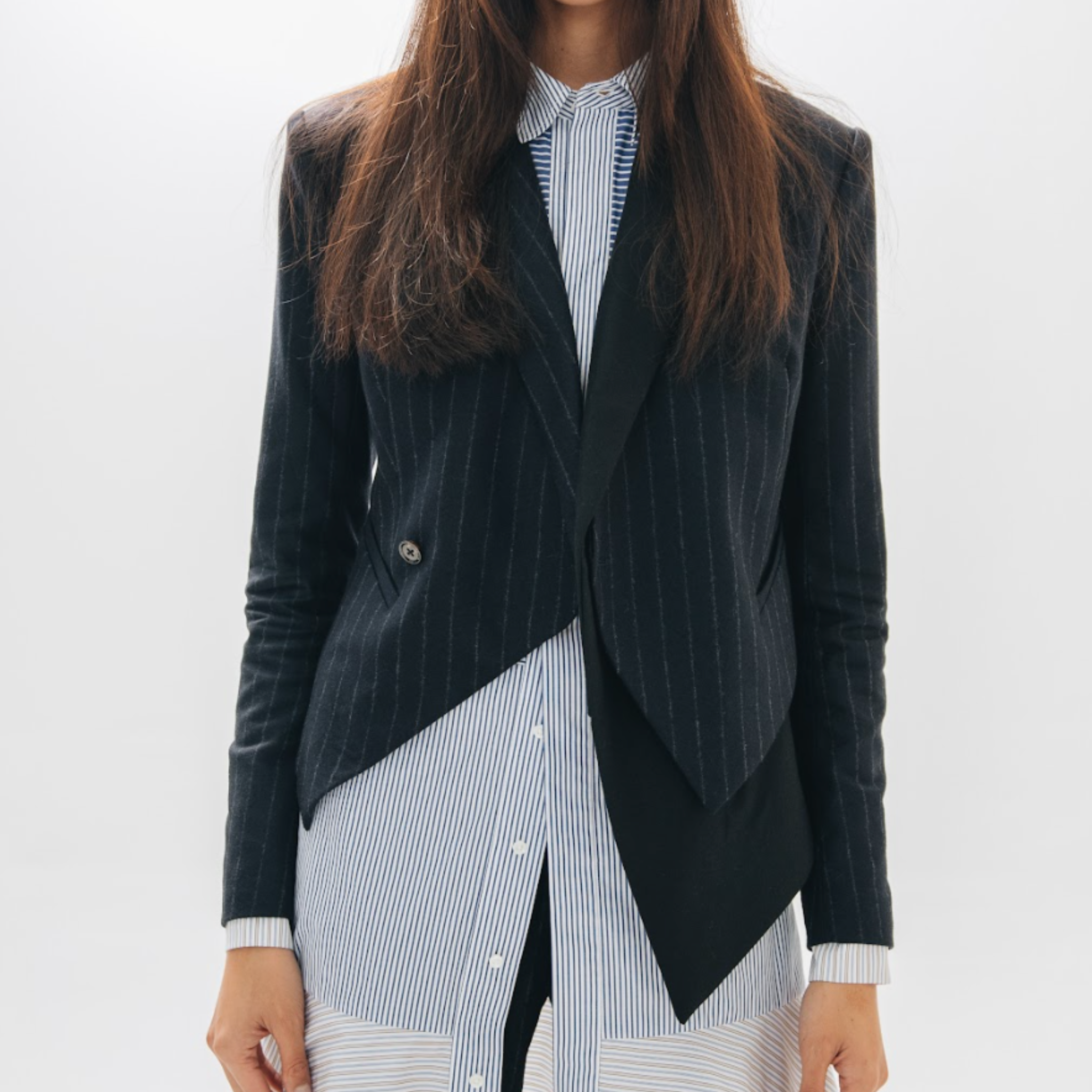 Person wearing a black pinstripe blazer over a striped shirt on a white background