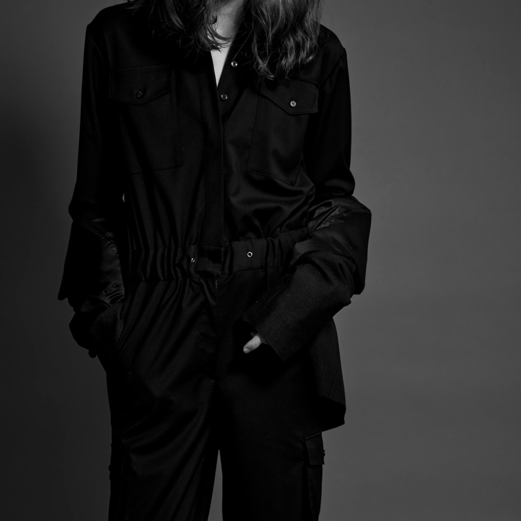 Person wearing a black outfit against a gray background