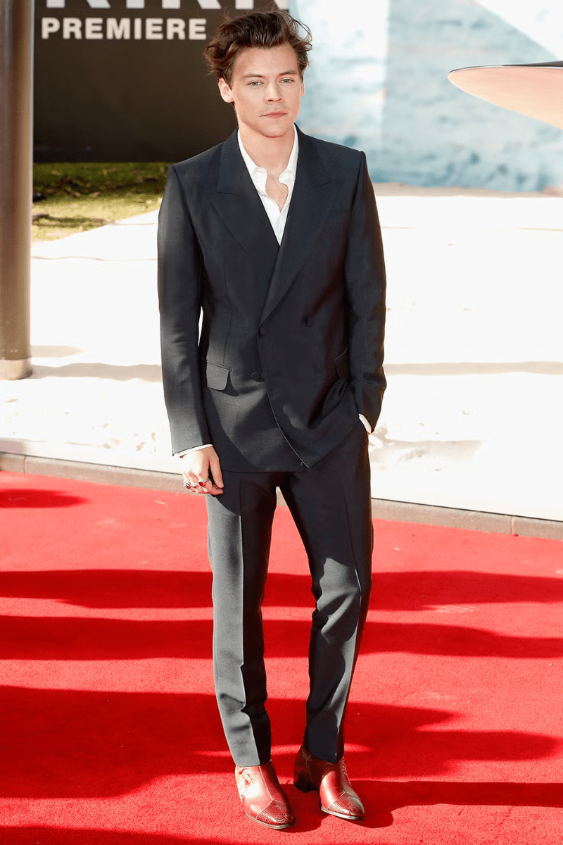 Harry Styles wearing a black suit on the red carpet.